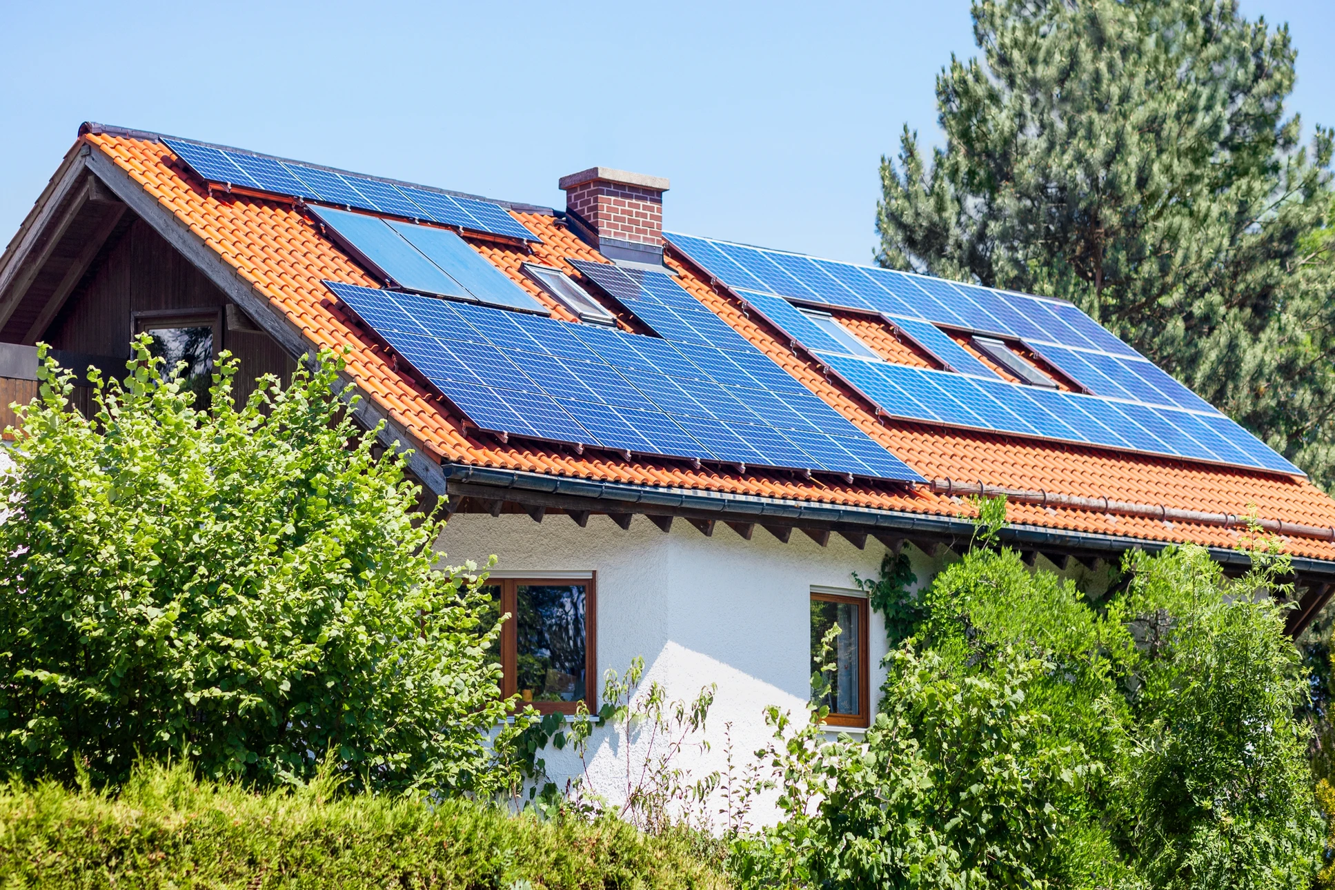 Vue aérienne d'un bâtiment commercial équipé de panneaux solaires photovoltaïques sur toiture bleue ondulée, au coucher du soleil