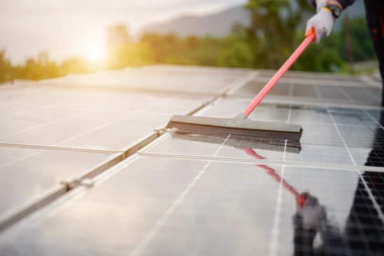 Extérieur, technicien avec gants noirs nettoie panneau solaire photovoltaïque avec jet d'eau haute pression