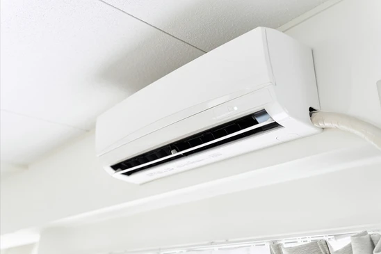 Technicien installant une unité extérieure de climatisation sur façade en briques