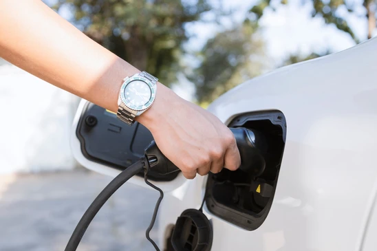 Scène extérieure urbaine avec véhicule électrique blanc en charge sur borne publique